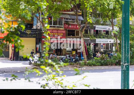 Hanoi, Vietnam - 28 mai 2023 : une rue vibrante bourdonne de vie alors que les habitants se rassemblent dans un restaurant animé au bord de la route. Ils sont assis sur des tabourets bas, partageant la rire Banque D'Images