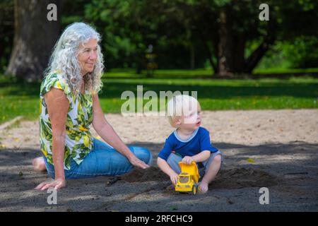 Une grand-mère regarde son petit-fils jouer dans le sable Banque D'Images