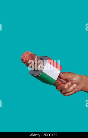 gros plan d'un homme tenant un micro modelé avec le drapeau de l'italie sur un fond bleu Banque D'Images