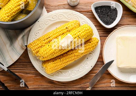 Assiette d'épis de maïs bouillis avec du beurre sur fond de bois Banque D'Images