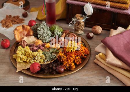 Matériel végétal pour la teinture organique des tissus sur un plat, pile de tissus teints à la main sur le fond de la poitrine en bois avec des tissus Banque D'Images