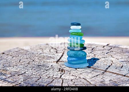 Pyramide équilibrée d'éclats de bouteilles en verre polis par la mer sur la surface en bois par la mer. Pyramide zen pour la méditation Banque D'Images