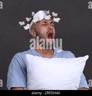 Insomnie. Homme fatigué avec oreiller bâillant. Illustrations de moutons courant autour de sa tête sur fond sombre Banque D'Images