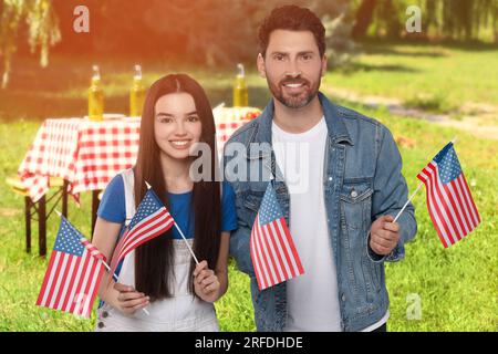 4 juillet - jour de l'indépendance de l'Amérique. Heureux père et fille avec drapeaux nationaux des États-Unis ayant pique-nique dans le parc Banque D'Images