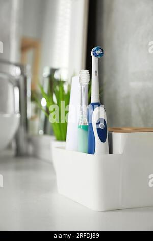 Brosses à dents électriques et tube de pâte sur comptoir blanc dans la salle de bain Banque D'Images
