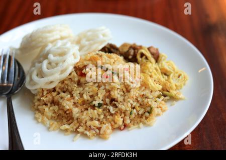 Nasi Goreng Spicy, riz frit avec biscuits aux crevettes Kerupuk. Servi sur une assiette blanche Banque D'Images