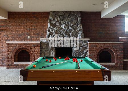 Une table de billard à l'intérieur d'une salle de loisirs au sous-sol avec une cheminée en pierre. Banque D'Images