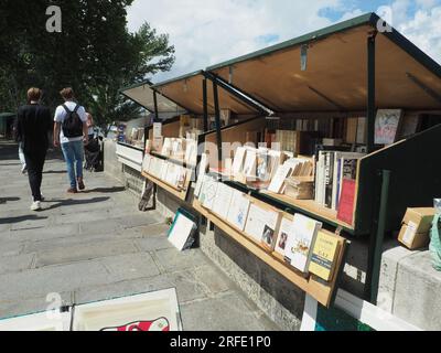 Paris, France. 29 juillet 2023. Les passants passent devant les étals de livres des Bouquinistes de Paris sur les bords de Seine. Des centaines de boîtes célèbres seront retirées pour la cérémonie d’ouverture des Jeux Olympiques. Crédit : Rachel Boßmeyer/dpa/Alamy Live News Banque D'Images