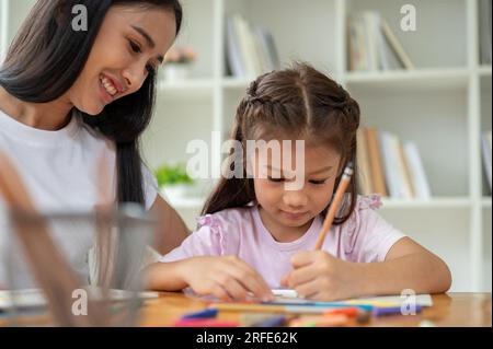 Une gentille et belle enseignante asiatique ou baby-sitter est baby-sitting et enseigner l'art à une jeune fille adorable à la maison. Concept d'éducation Banque D'Images