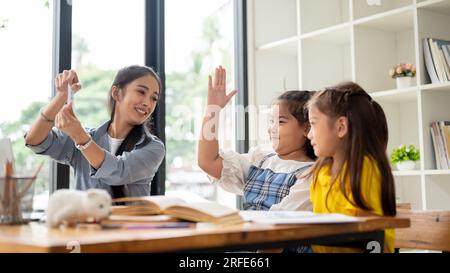 Deux adorables jeunes filles asiatiques aiment étudier les cartes-éclair de l'alphabet anglais avec un professeur privé à la maison. préscolaire, maternelle, élémentaire s Banque D'Images