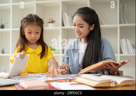 Une adorable petite fille d'âge préscolaire asiatique se concentre sur l'étude des cartes-éclair de l'alphabet anglais avec un professeur particulier gentil à la maison. préscolaire, jardin d'enfants Banque D'Images