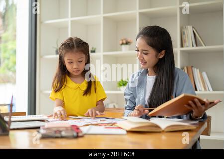 Une adorable petite fille d'âge préscolaire asiatique se concentre sur l'étude des cartes-éclair de l'alphabet anglais avec un professeur particulier gentil à la maison. préscolaire, jardin d'enfants Banque D'Images