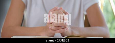 Une femme lit un livre épais et prie en gros plan. Banque D'Images