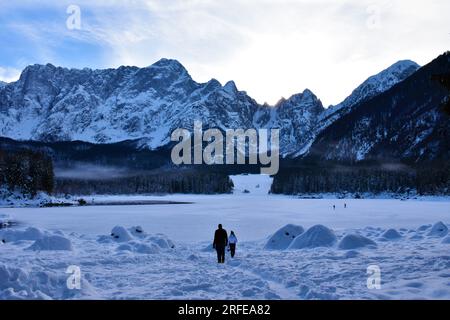 Vue sur le lac gelé lago di fusine superiore près de Tarvisio dans la région Frioul-Vénétie Julienne en Italie et la montagne Mangart dans les alpes juliennes en hiver Banque D'Images