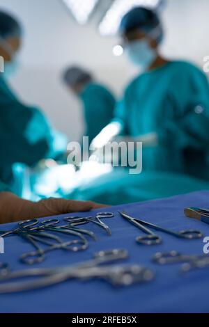 Gros plan des instruments chirurgicaux sur divers chirurgiens opérant sur un patient en salle d'opération Banque D'Images