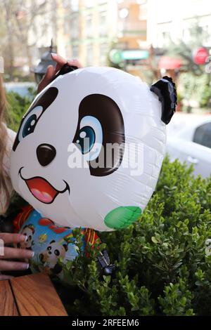 Une femme tient un ballon de panda dans sa main Banque D'Images