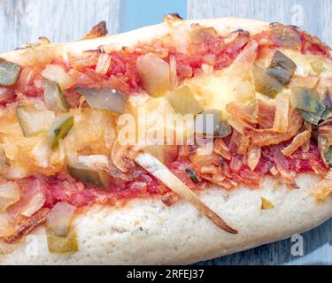 Hot Dog : un délicieux hot dog rempli de cornichons savoureux, d'oignons frits et d'un soupçon de sauce tomate, capturé dans une photo alléchante d'en haut sur un g. Banque D'Images