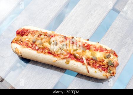 Hot Dog : un délicieux hot dog rempli de cornichons savoureux, d'oignons frits et d'un soupçon de sauce tomate, capturé dans une photo alléchante d'en haut sur un g. Banque D'Images