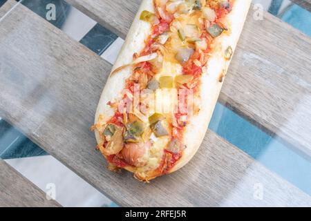 Hot Dog : un délicieux hot dog rempli de cornichons savoureux, d'oignons frits et d'un soupçon de sauce tomate, capturé dans une photo alléchante d'en haut sur un g. Banque D'Images