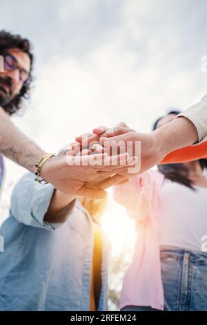 Vertical. Vue à angle bas d'un groupe de jeunes empilant les mains ensemble, collaborant pour un projet de travail. Les meilleurs collègues mettent les mains les uns sur les autres. Unité et partenariat. Photo de haute qualité Banque D'Images