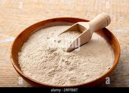 Poudre de farine d'enveloppe de psyllium sur un bol en bois et cuillère à l'intérieur à la maison. Avantages pour la santé du concept de farine de psyllium. Banque D'Images