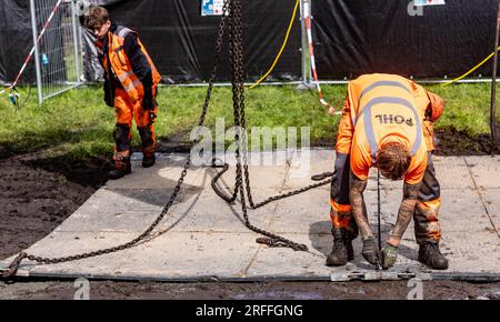 Wacken, Allemagne. 03 août 2023. Les techniciens placent des panneaux flexibles sur les chemins boueux pour permettre le passage. Le Wacken Open-Air (WOA) du 2 au 5 août est considéré comme le plus grand festival de heavy Metal au monde. Crédit : Axel Heimken/dpa/Alamy Live News Banque D'Images