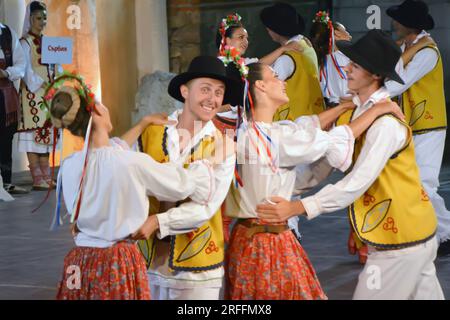 Un groupe de danseurs de la République de Serbie en costumes colorés exécutent une danse traditionnelle au XXI Festival International de folklore à anci Banque D'Images