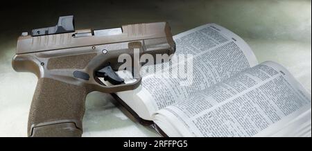 Pistolet chambré en 9 mm sur le dessus d'une bible ouverte sur le passage qui dit aux disciples de vendre leur manteau et d'acheter une épée Banque D'Images