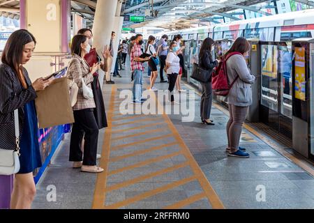 Passager avec téléphone portable à la gare Skytrain, Chong Nonsi, Bangkok, Thaïlande Banque D'Images