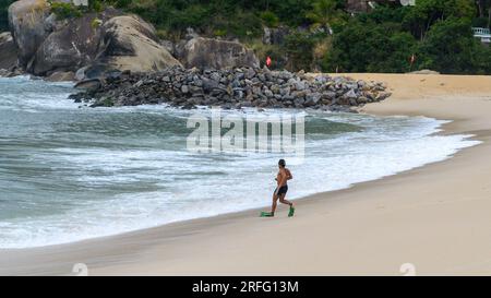 Niteroi, Brésil, Un brésilien se précipite vers l'eau de la plage portant des palmes d'entraînement dans ses pieds. C'est la saison hivernale. Banque D'Images