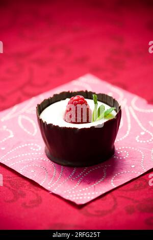 dessert à la mousse au chocolat blanc servi avec de la framboise fraîche et de la menthe dans une tasse de chocolat comestible Banque D'Images