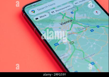 New York, États-Unis - 21 juillet 2023 : faire le meilleur itinéraire à travers les embouteillages à Vienne sur l'écran de smartphone vue rapprochée avec fond rouge Banque D'Images