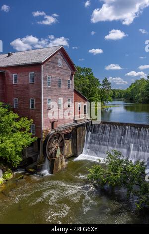 Un vieux moulin à grist rouge avec roue à eau et barrage. Banque D'Images