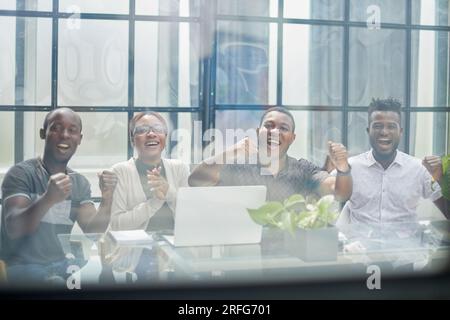 derrière le verre jeune équipe célébrant le succès discutant du projet dans le bureau moderne Banque D'Images