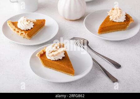 Tranche d'une tarte à la citrouille traditionnelle pour Thanksgiving garnie de crème fouettée sur fond clair Banque D'Images