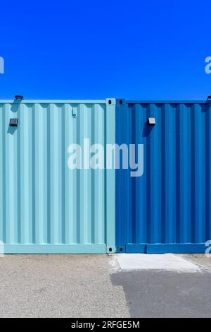 Conteneurs d'expédition colorés utilisés comme cafés et bars sur le Harbour Arm à Folkestone, Kent. Peint dans une combinaison de couleurs bleu foncé et sarcelle. Banque D'Images