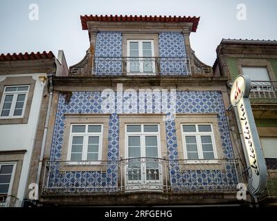 11 juin 2023, Caminha, Viana do Castelo, Portugal : une façade est décorée d'azulejos bleus et blancs. 'Azulejos'' est le mot portugais pour les tuiles. Son origine est, bien sûr, arabe, et cela signifie «petite pierre polie». Les tuiles ont d'abord été apportées au Portugal par les Arabes, au 13e siècle au moment de leur invasion, ce qui a également contribué à façonner la culture portugaise. Il s'agissait initialement de carreaux de sol en mosaïque, souvent pour les églises ou les cloîtres. Au fil du temps, la tendance était de les utiliser dans la construction de chaque bâtiment, il est donc possible de les voir presque partout. La décoration i Banque D'Images