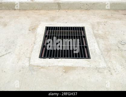 La grille de couverture de drain sur la rue en béton pour le système de drainage près de la nouvelle gare est en construction, vue de face avec l'espace de copie. Banque D'Images