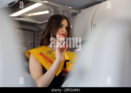 Heathrow London Airport England agent de bord démontrant les procédures de sécurité portant un gilet de sauvetage gonflable avant le vol Banque D'Images