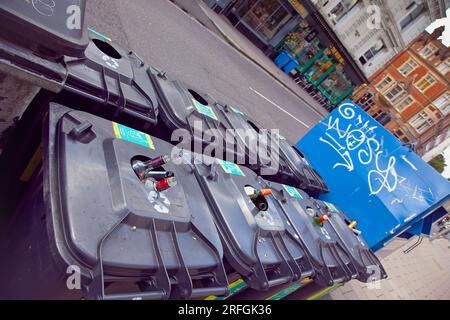 Angleterre, East Sussex, Brighton, Hove, Western Road, Bacs pleins sur des bouteilles sur le trottoir. Banque D'Images