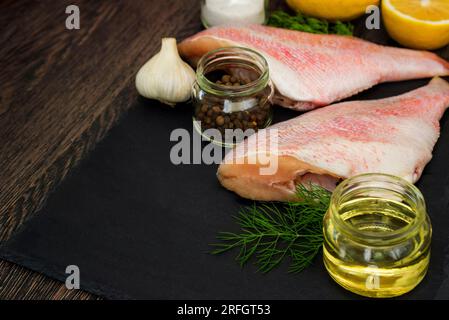 Perche de mer sur tableau noir. Bar de mer sur tableau noir avec des ingrédients pour la cuisson Banque D'Images