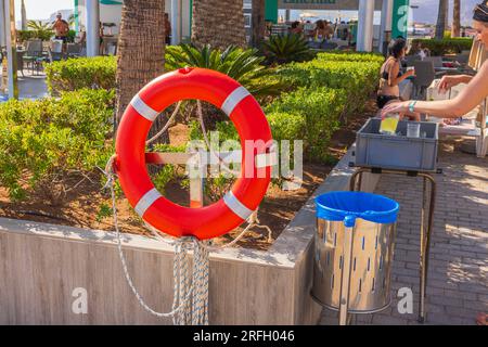 Vue de la place près de la piscine extérieure de l'hôtel avec bouée de sauvetage rouge, corbeille et plateau pour les gobelets usagés. Gran Canaria, Espagne. Banque D'Images