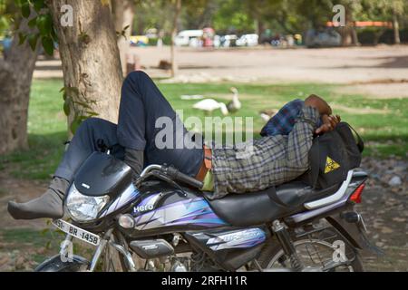 Inde, New Delhi - 26 mars 2018 : motocycliste dormant sur une moto dans un parc de la ville Banque D'Images