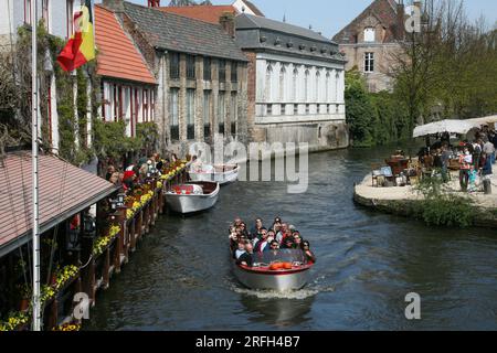 ViewPoint de Dijver à Bruges, Belgique. Excursion en bateau touristique sur le canal de Dijver occupé par les touristes et un marché aux puces sur le parc de Dijver. Tourisme en bord de rivière Banque D'Images