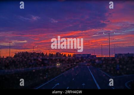 lever de soleil flou sur l'autoroute à travers le verre sale du bus. Banque D'Images