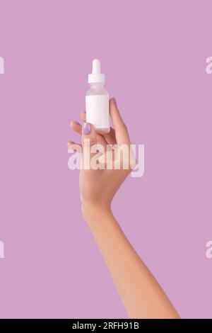 Les femmes tiennent main compte-gouttes avec du sérum sur fond de lavande pastel Banque D'Images