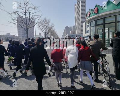 Pyongyang, 29 mars 2018. Les orphelins des martyrs retraçant le parcours de Kim il Sung sont accueillis par des personnes en rouge et vert. Banque D'Images