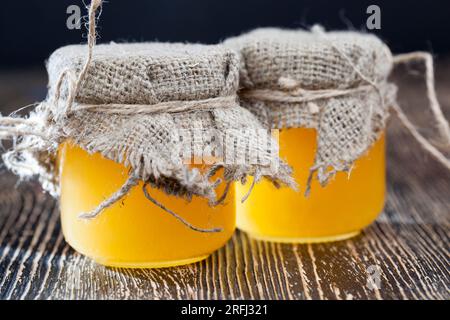 deux pots de miel en verre sont recouverts de couvercles et d'un chiffon de lin, miel d'abeille frais emballé dans des pots en verre Banque D'Images