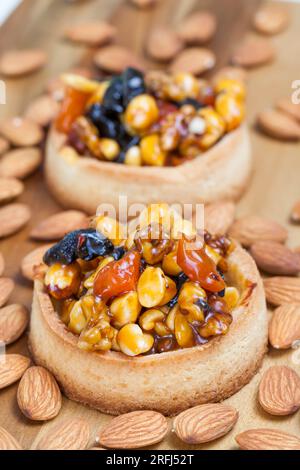 tartelette de pâte de blé avec noix et fruits secs à la crème caramel, tartelette de blé avec garniture sucrée, tartelette croustillante avec noisettes, cacahuètes et autres Banque D'Images