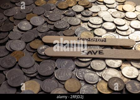 Une photo en gros plan de pièces de roupies indiennes étalées sur une table, avec le mot « Pension Save » écrit dans un bâton Banque D'Images